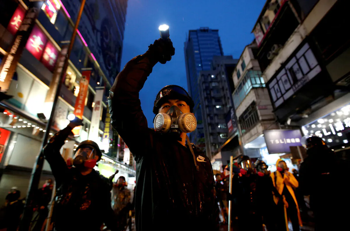 Demonstrators protesting the proposed extradition bill aim their flashlights towards riot police as they are chased through the streets of Hong Kong, on Aug. 25, 2019. (Willy Kurniawan/Reuters)