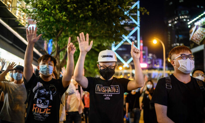 Pro-democracy protesters gesture the slogan 'five demands and not one less' during a vigil outside the Pacific Place shopping mall in the Admiralty area of Hong Kong on May 15, 2020, to mark the 11 month anniversary since a man fell to his death from a scaffolding, during a protest against the Hong Kong government's extradition bill last year. (Anthony Wallance/AFP via Getty Images)