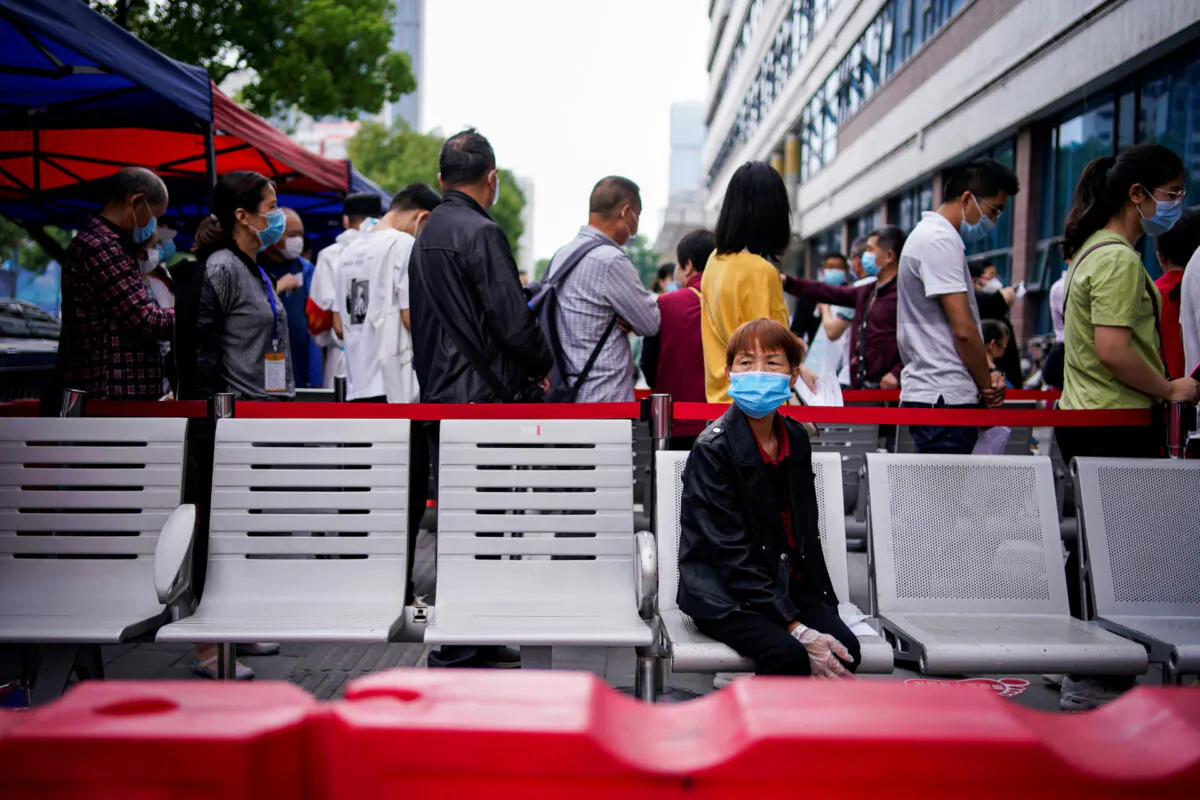 A woman wearing a face mask looks on in front of others standing in a queue for nucleic acid testings in Wuhan, the Chinese city hit hardest by the coronavirus disease (COVID-19) outbreak, Hubei province, China May 16, 2020. (Aly Song/Reuters)