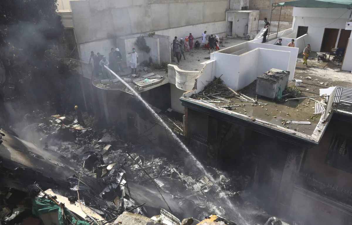 Fire brigade staff try to put out fire caused by plane crash in Karachi, Pakistan, on May 22, 2020. (Fareed Khan/AP Photo)