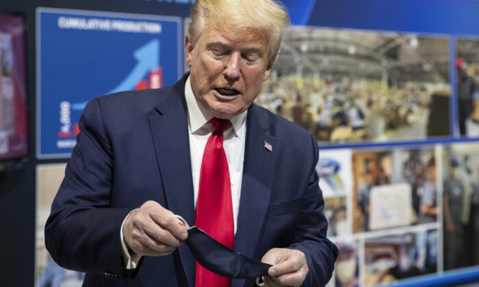 President Donald Trump holds his mask as he speaks while touring Ford's Rawsonville Components Plant, in Ypsilanti, Mich., on May 21, 2020. (Alex Brandon/AP Photo)