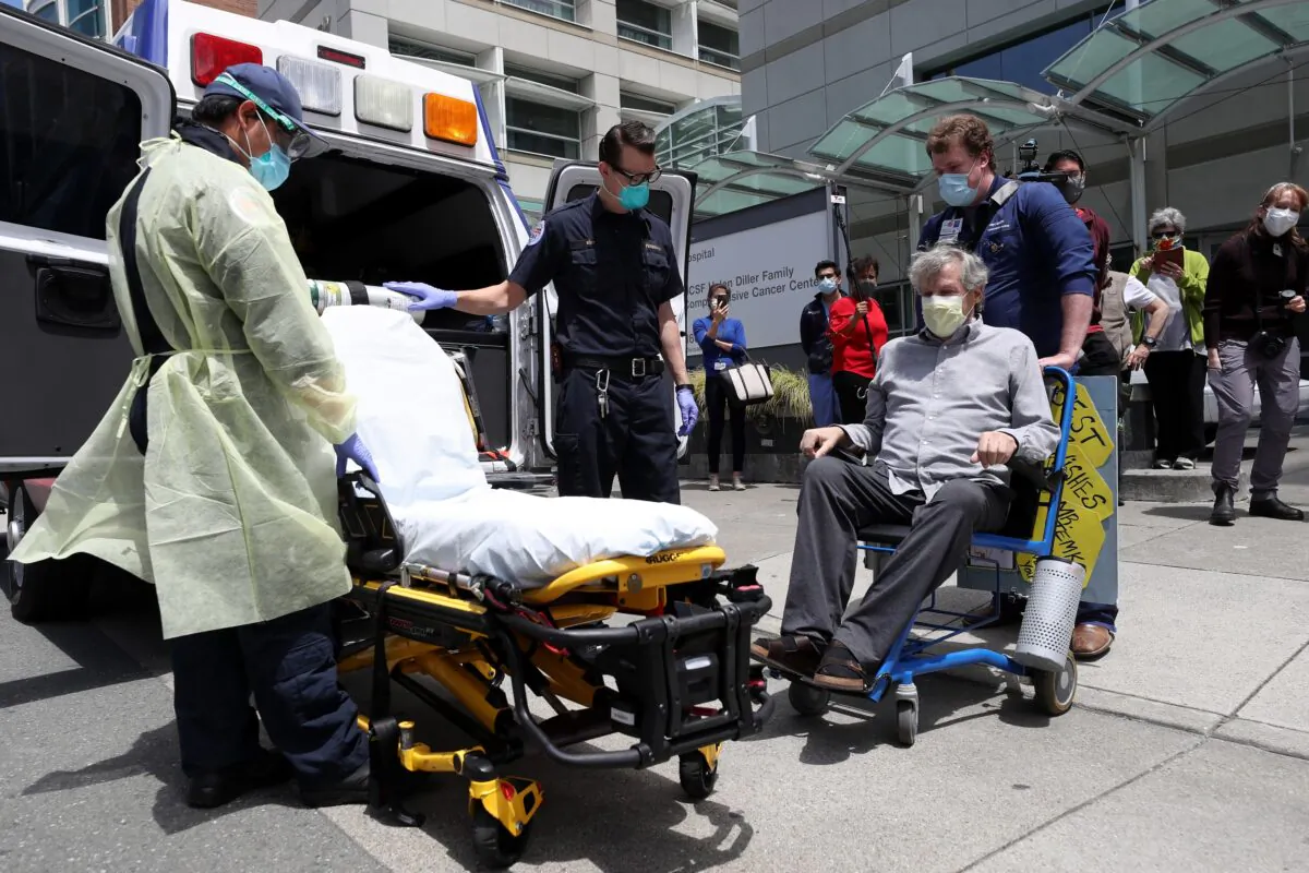 Ronald Temko, sitting, a COVID-19 patient, prepares to be loaded into an ambulance after discharge from the UCSF Medical Center at Mount Zion in San Francisco, Calif., on May 20, 2020. (Justin Sullivan/Getty Images)