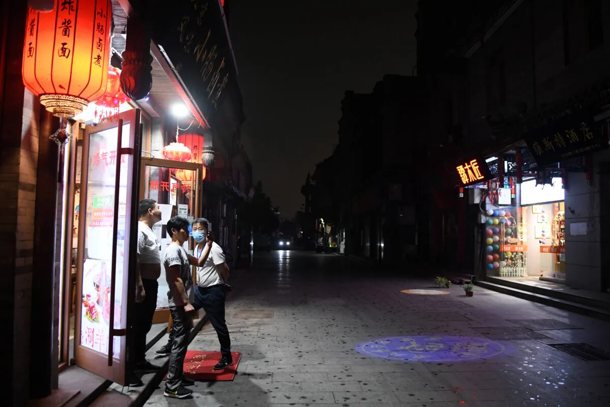 A group of men take photos as the sky goes dark in the mid afternoon amid an approaching thunderstorm in an alley south of Beijing's Tiananmen Square, during the opening ceremony of the Chinese People's Political Consultative Conference (CPPCC) in Beijing, China on May 21, 2020. (GREG BAKER/AFP via Getty Images)