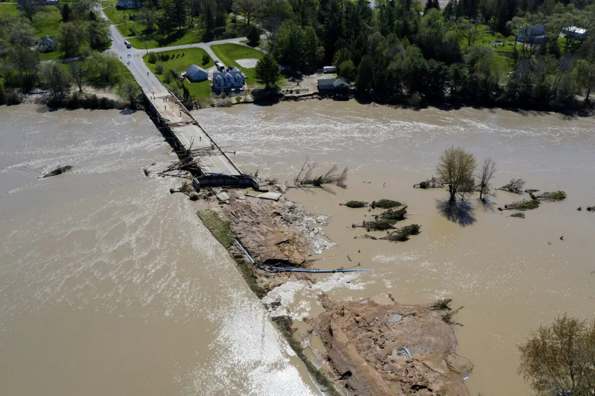 People survey the flood damage to the Curtis Road Bridge in Edenville, Mich., on May 20, 2020. (Neil Blake/The Grand Rapids Press via AP)