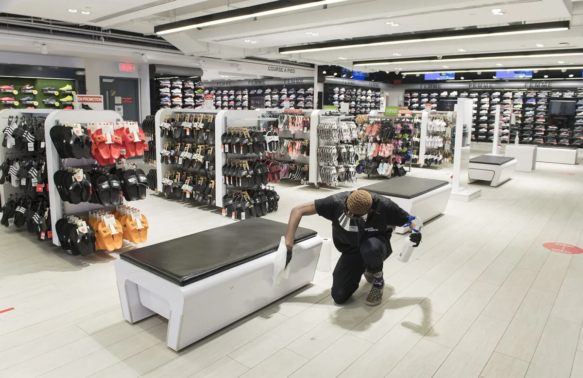 Liam Slater Oda, an employee with Sports Experts disenfects a bench at the store on Sainte-Catherine street in Montreal, on May 24, 2020. THE CANADIAN PRESS/Graham Hughes