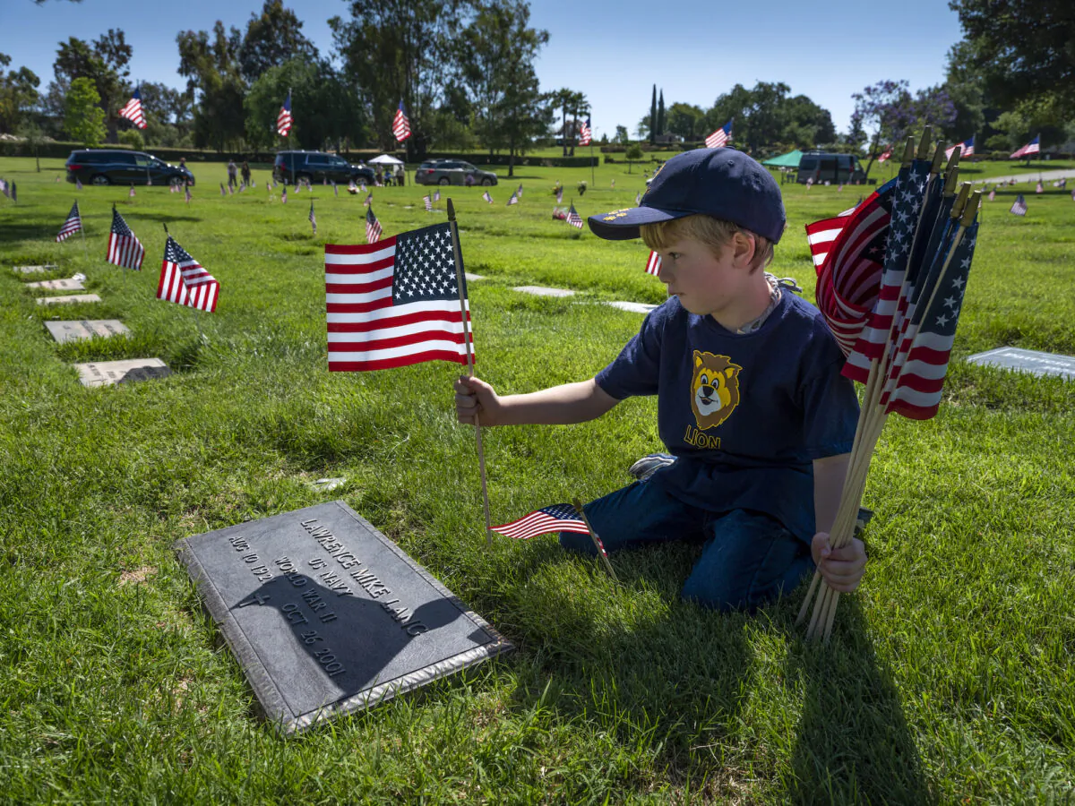 Ethan Burdzinski, 6, places flags on a veterans grave in the Pierce Brothers memorial park in Westlake on May 23, 2020 in Los Angeles, California. (Brent Stirton/Getty Images)