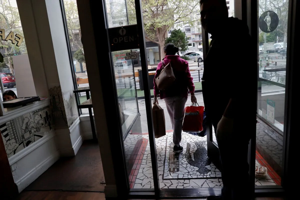 An employee of Farley’s East Cafe, which closed due to the financial crisis caused by the CCP virus, carries donated food items after being laid off from the cafe in Oakland, Calif., on March 18, 2020. (Shannon Stapleton/Reuters)