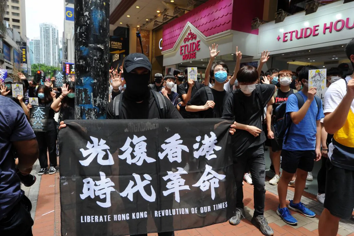 A protester holds up a banner with the words “Liberate Hong Kong, Revolution of Our Time” at a protest in Causeway Bay, Hong Kong, on May 24, 2020. (Song Bilung/The Epoch Times)