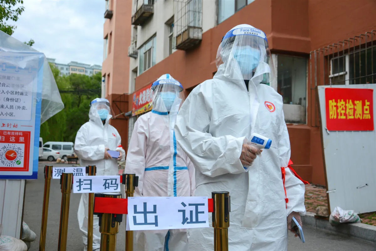 Staff waiting to check people’s entering permit, screen their body temperature, and scan their health codes at the entrance of a residential compound in Jilin city, China, on May 25, 2020. (STR/AFP via Getty Images)