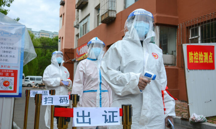 Staff wait to check people’s entering permit, screen their body temperature, and scan their health codes at the entrance of a residential compound in Jilin city, China, on May 25, 2020. (STR/AFP via Getty Images)