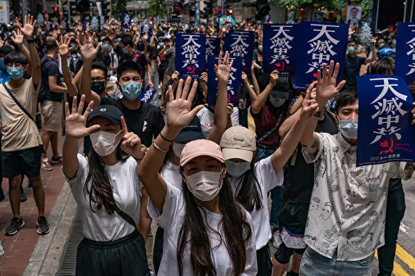 A protest against Beijing’s proposed National Security Law on Hong Kong Island in Hong Kong on May 24, 2020. The marchers hold up five fingers symbolizing their demands and hold signs saying "Heaven Is Eliminating the CCP." (Anthony Wallace/AFP via Getty Images)