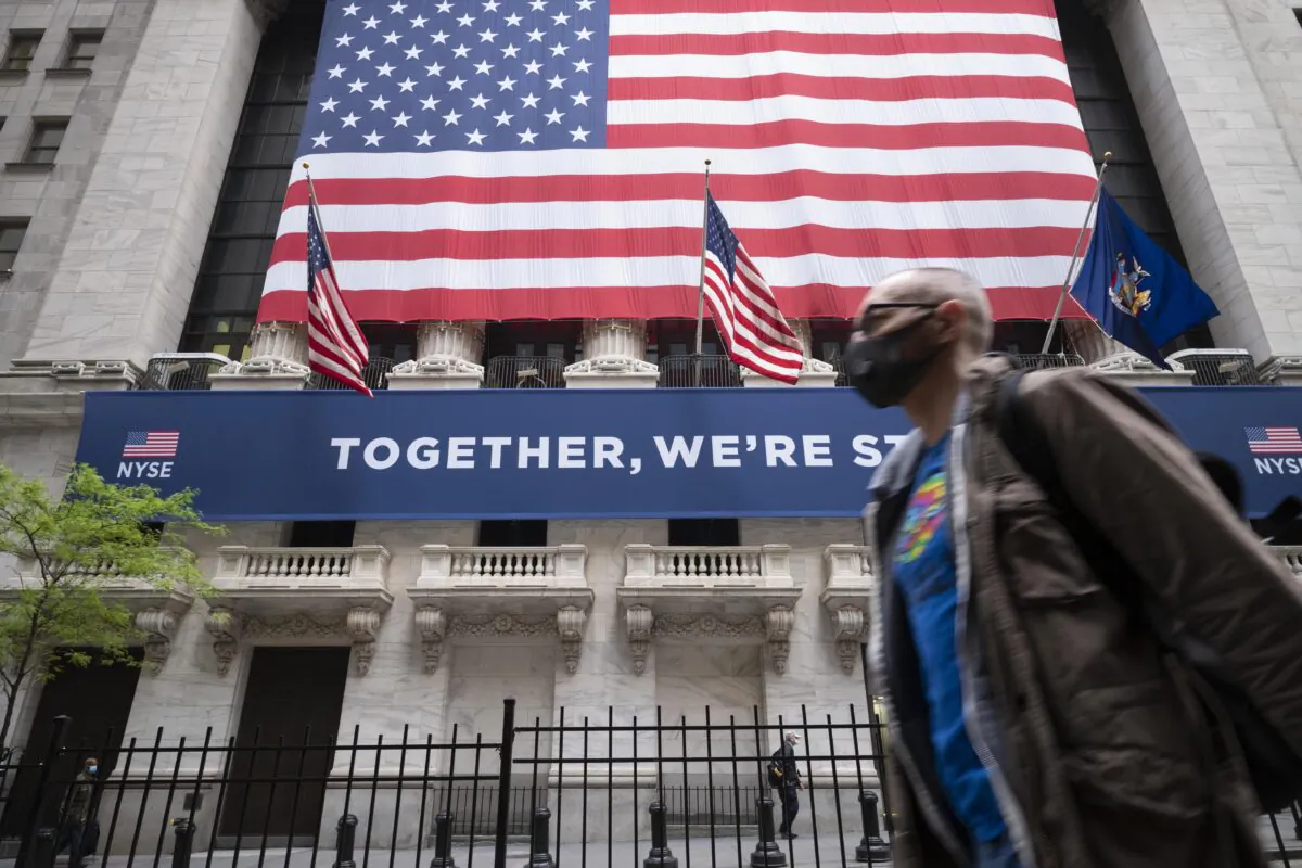 A man wearing a protective face mask passes the New York Stock Exchange, as employees arrive for the partial reopening of the trading floor, N.Y., on May 26, 2020. (Mark Lennihan/AP Photo)