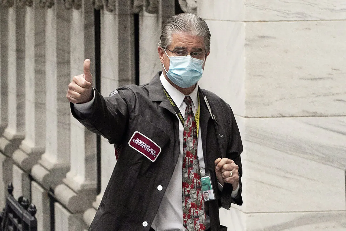 Trader Daniel Krieger signals a thumbs-up as he arrives at the New York Stock Exchange where the trading floor reopens in Manhattan, N.Y., on May 26, 2020. (Mark Lennihan/AP Photo)