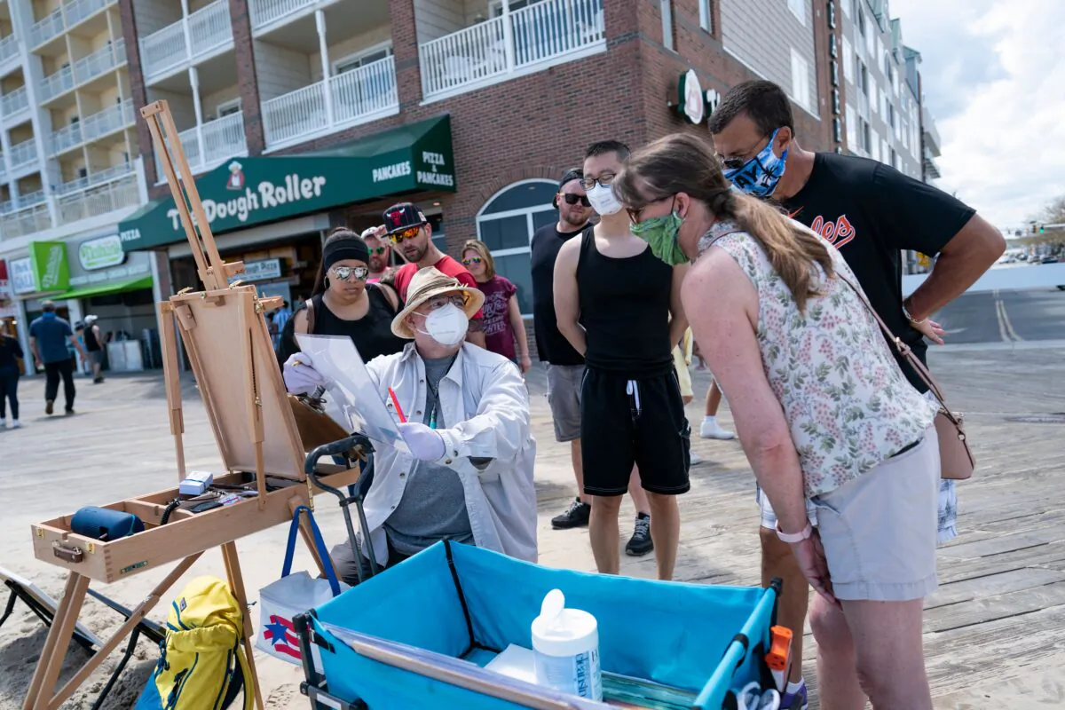 A local artist and onlookers wear masks on the boardwalk during the Memorial Day holiday weekend in Ocean City, Md., on May 23, 2020. (Alex Edelman/AFP via Getty Images)