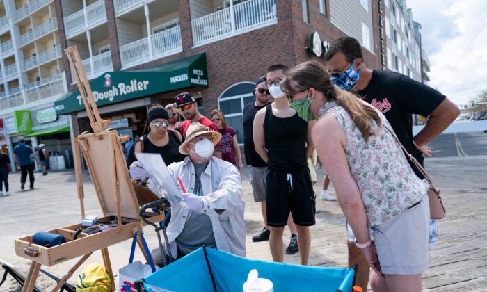 A local artist and onlookers wear masks on the boardwalk during the Memorial Day holiday weekend in Ocean City, Md., on May 23, 2020. (Alex Edelman/AFP via Getty Images)