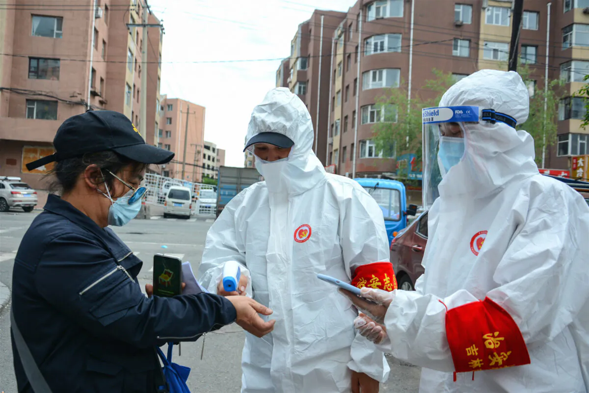 Staff are screening the body temperature of a resident outside a residential compound in Jilin city, China on May 25, 2020. (STR/AFP via Getty Images)
