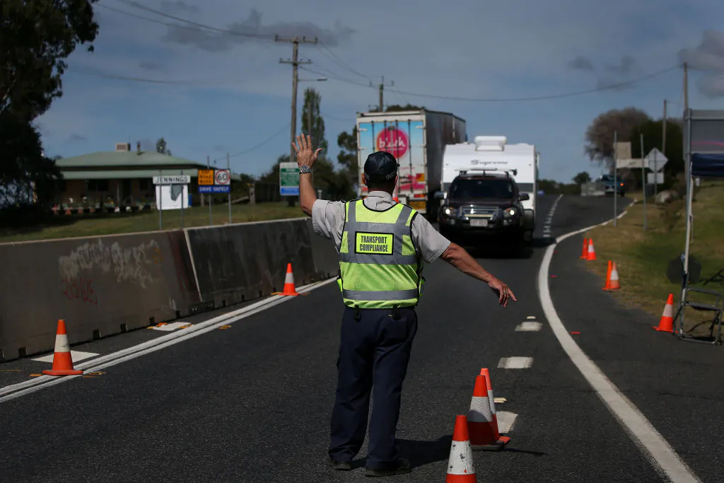 A Queensland Transport Inspector signals to a driver approaching the border in Wallangarra, Australia on April 2. (Lisa Maree Williams/Getty Images)