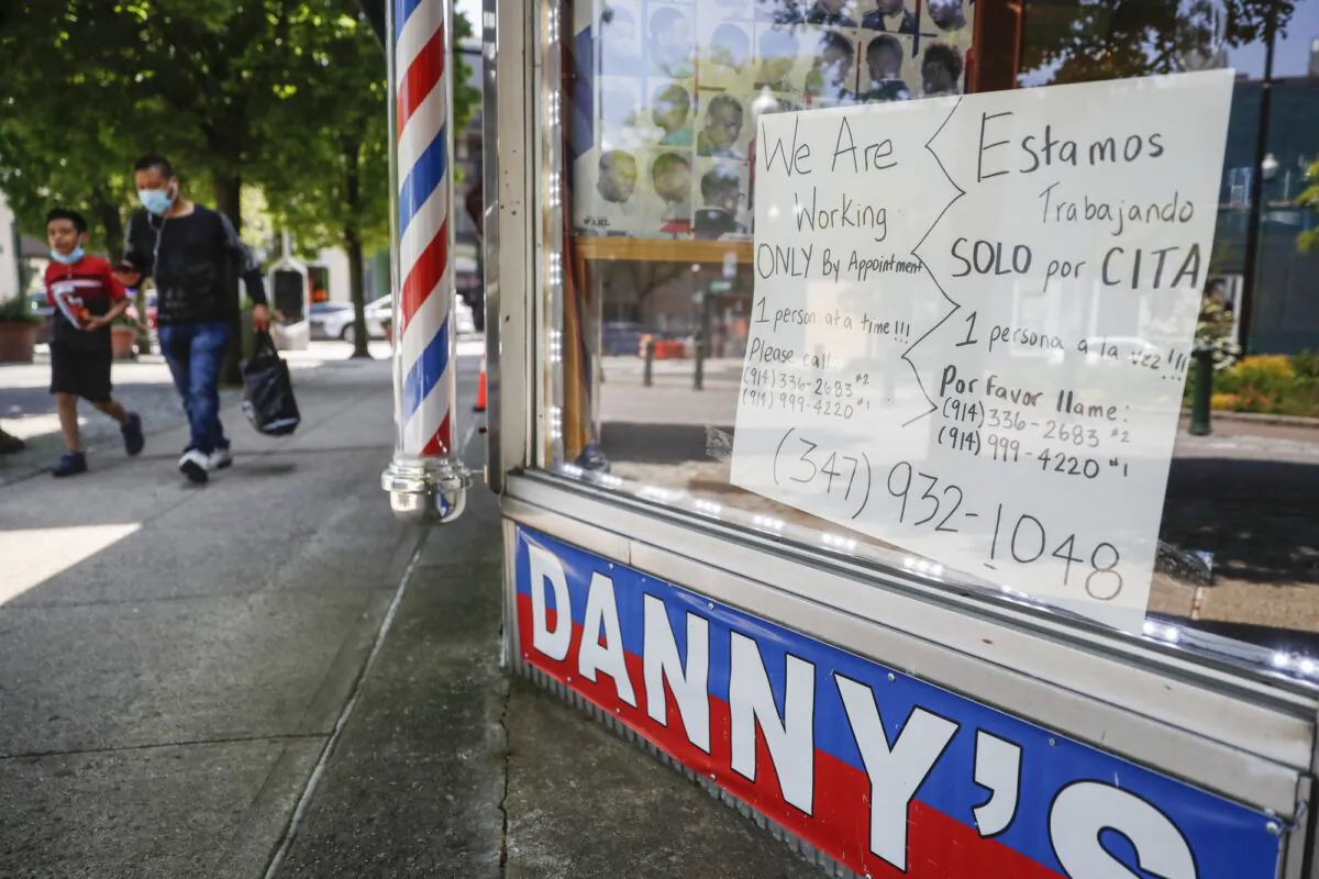 Pedestrians pass a barbershop that displays a sign advertising haircuts by appointment only in New Rochelle, N.Y., on May 26, 2020. (John Minchillo/AP Photo)