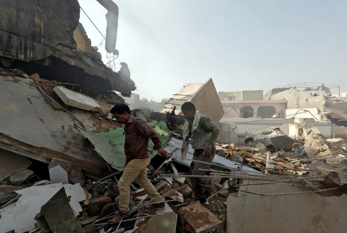 Men walk on the debris at the site of a passenger plane crash in a residential area near an airport in Karachi, Pakistan, on May 22, 2020. (Akhtar Soomro/File Photo/Reuters)