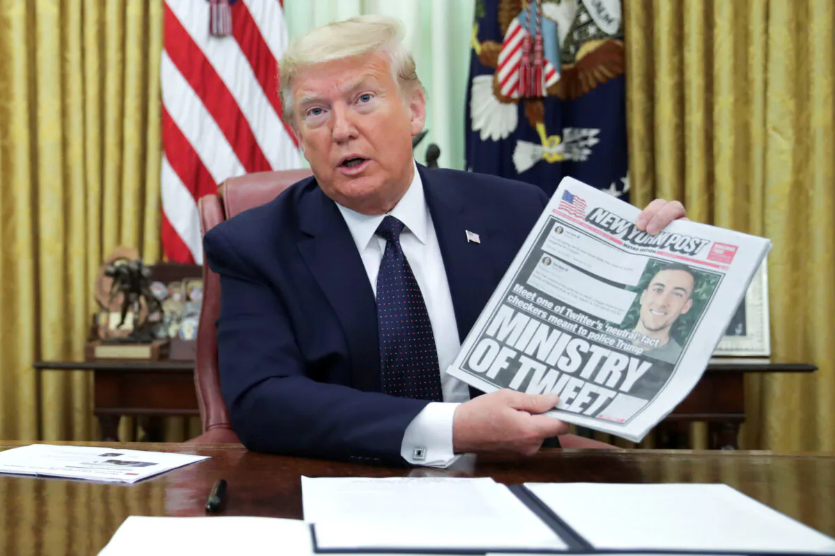 President Donald Trump holds up a front page of the New York Post as he speaks to reporters while he signing an executive order on social media companies in the Oval Office of the White House in Washington, on May 28, 2020. (Jonathan Ernst/Reuters)
