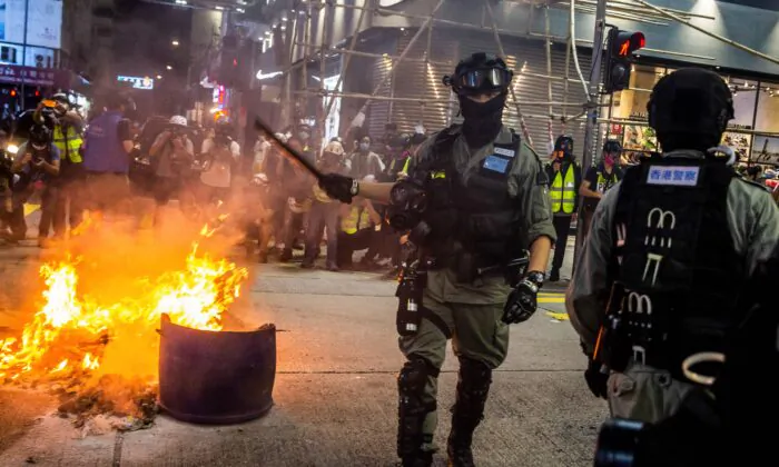 Police clear a road around a fire that was lit during a pro-democracy protest in the Mong Kok district of Hong Kong on May 27, 2020. (Isaac Lawrence/AFP via Getty Images)