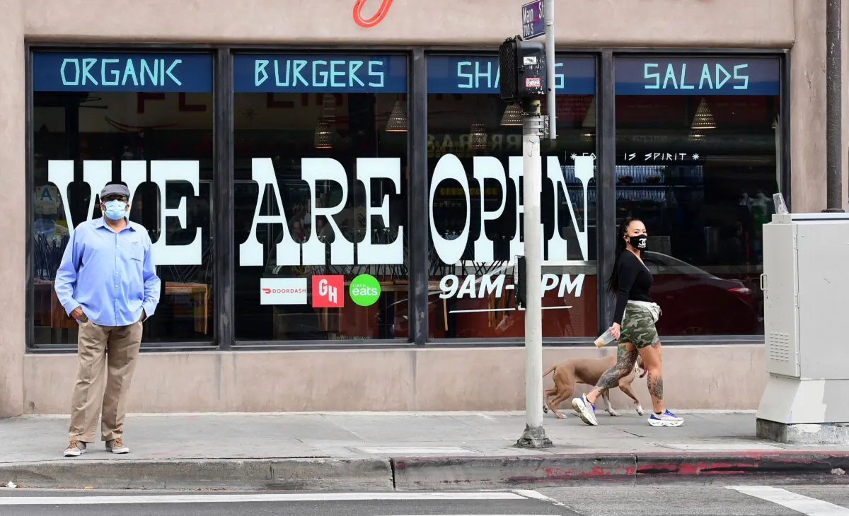 Pedestrians wear protective masks in front of a restaurant in Los Angeles, Calif., on May 12, 2020. (Frederic J. Brown/AFP/Getty Images)