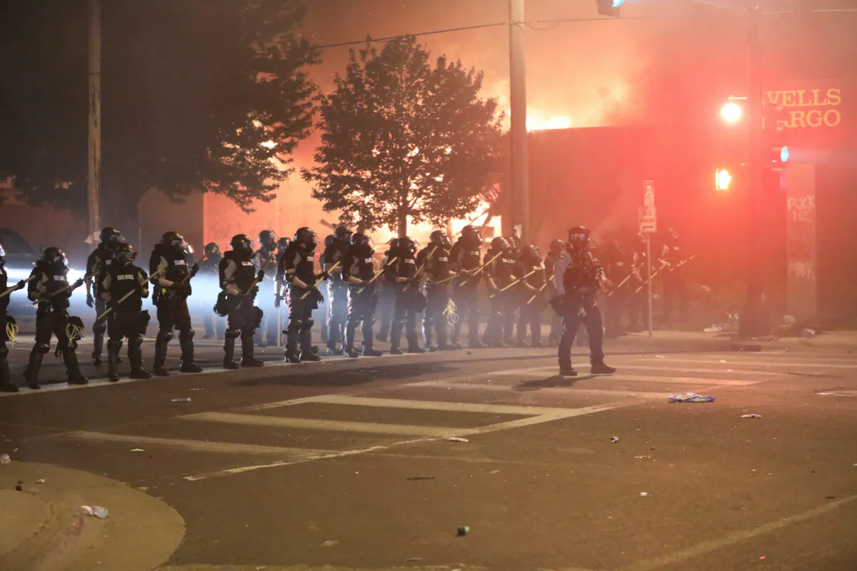 Police take back the streets at around midnight after firing copious amounts of tear gas to disperse protesters and rioters outside the Minneapolis Police 5th Precinct during the fourth night of protests and violence following the death of George Floyd, in Minneapolis, Minn., on May 29, 2020. (Charlotte Cuthbertson/The Epoch Times)