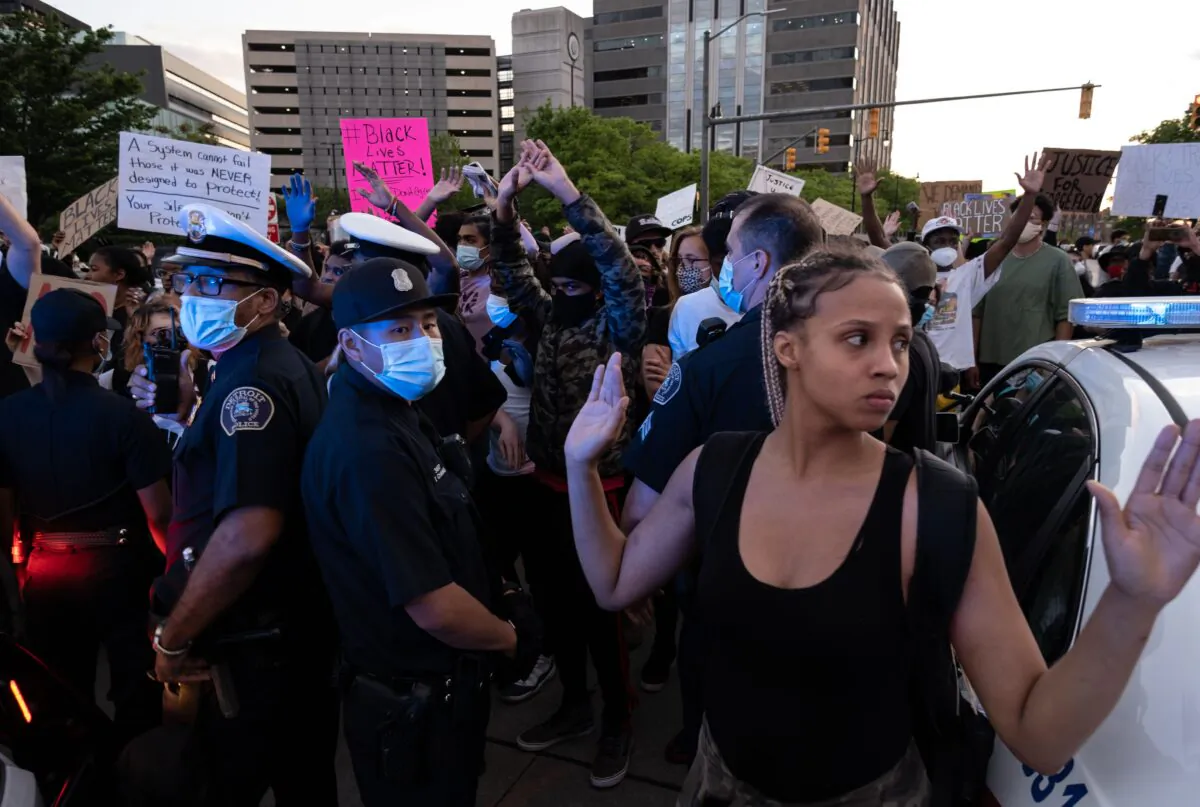Protesters hold their hands up and chant hands up dont shoot, while Detroit Police officers look on, during a protest in the city of Detroit, Michigan, on May 29, 2020. (Photo by Seth Herald/AFP via Getty Images)