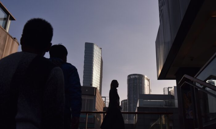 People walk between buildings at a shopping mall in Beijing on October 18, 2018. (GREG BAKER/AFP via Getty Images)