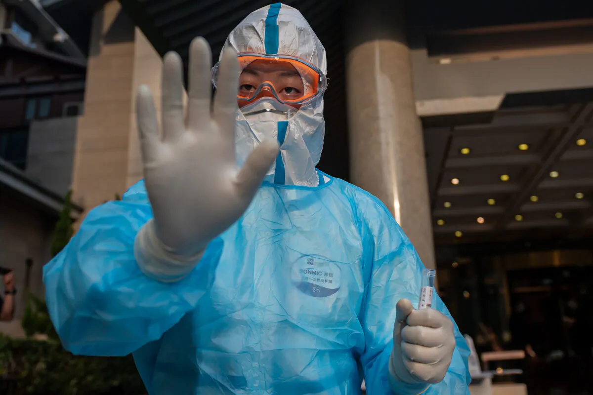 A medical worker wearing full protective gear gestures as he prepares to take swab samples from a journalist (not pictured) to test for COVID-19 at the Diaoyutai hotel in Beijing on May 28, 2020. (Nicolas Asfouri/AFP via Getty Images)