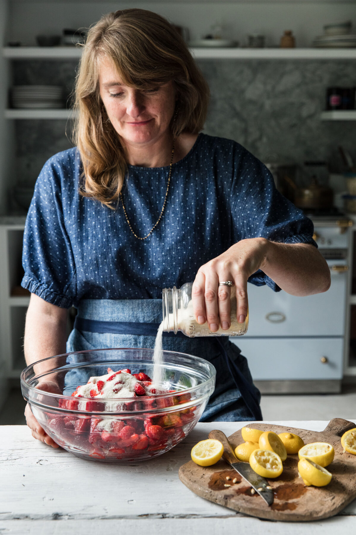 Woman mixes strawberries with sugar and lemon juice to make jam