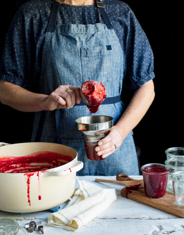 pouring strawberry jam into jars