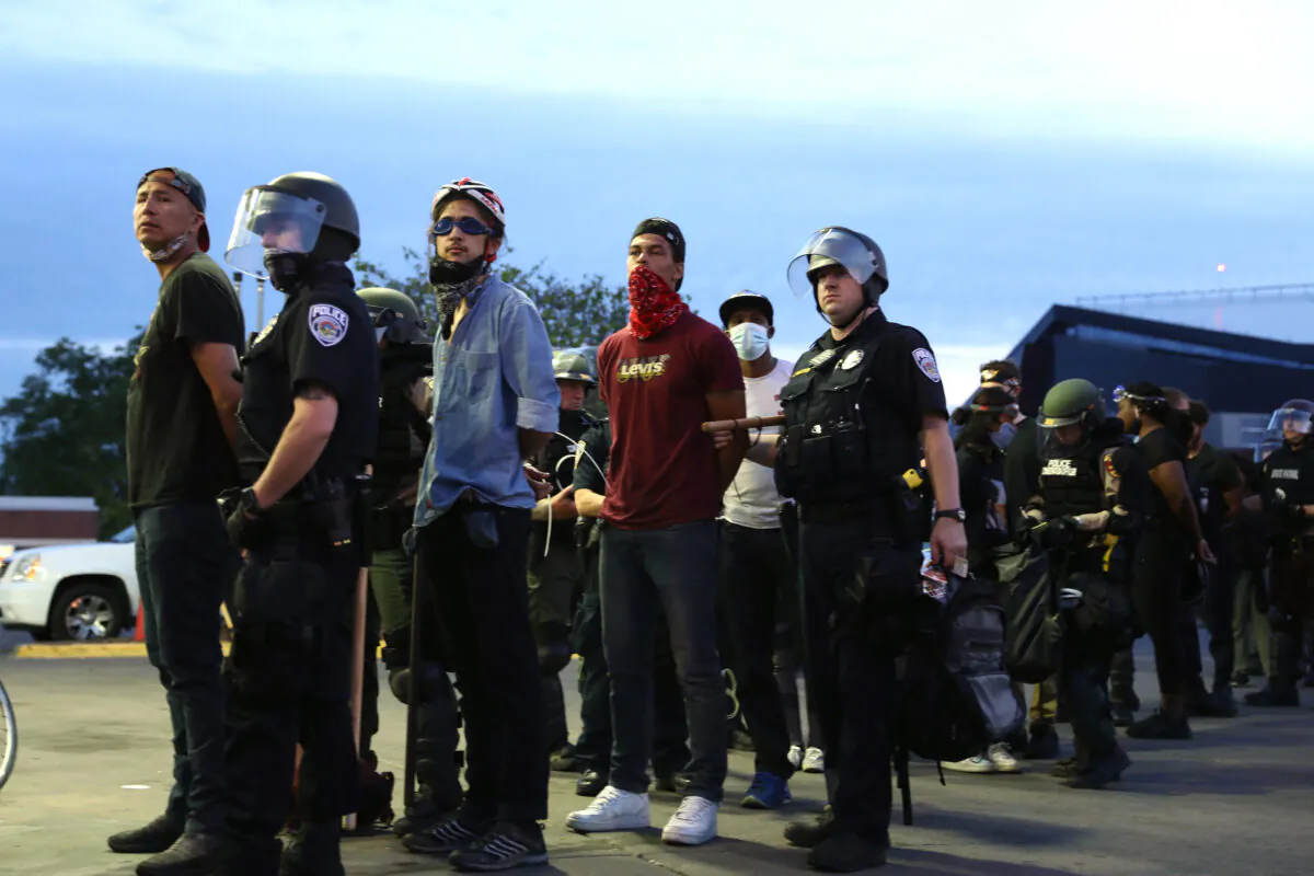 Protesters are detained by State Police after staying out beyond the governor’s 8 p.m. curfew during the sixth night of protests and violence following the death of George Floyd, in Minneapolis, Minn., on May 31, 2020. (Charlotte Cuthbertson/The Epoch Times)