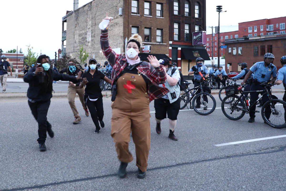 Protesters run from police officers before being detained during the sixth night of protests and violence following the death of George Floyd, in Minneapolis, Minn., on May 31, 2020. (Charlotte Cuthbertson/The Epoch Times)