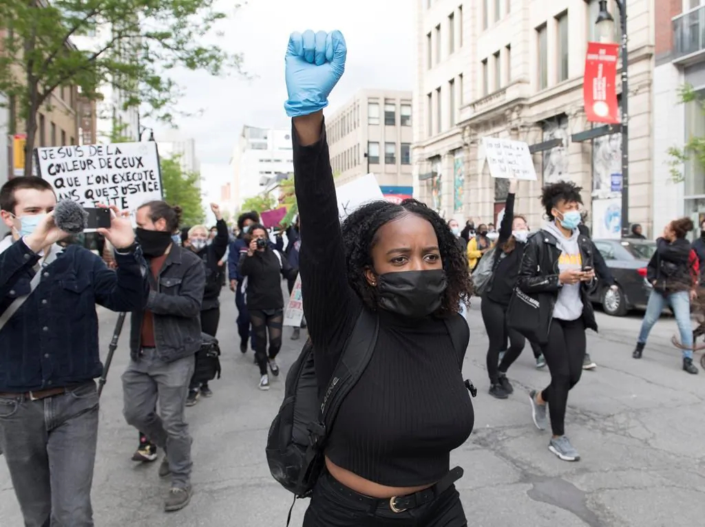 A woman raises her fist during a demonstration calling for justice for George Floyd in Montreal, May 31, 2020. (Graham Hughes/The Canadian Press)