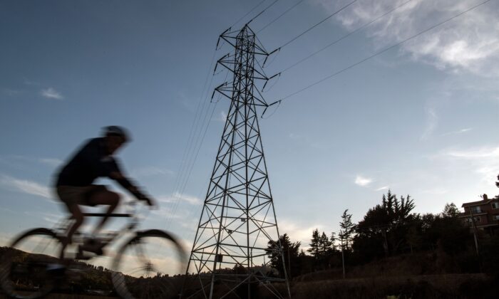 A bicyclist rides passed high-tension power lines in Mill Valley, California as a statewide blackout continues on October, 10, 2019. (Josh Edelson/AFP via Getty Images)