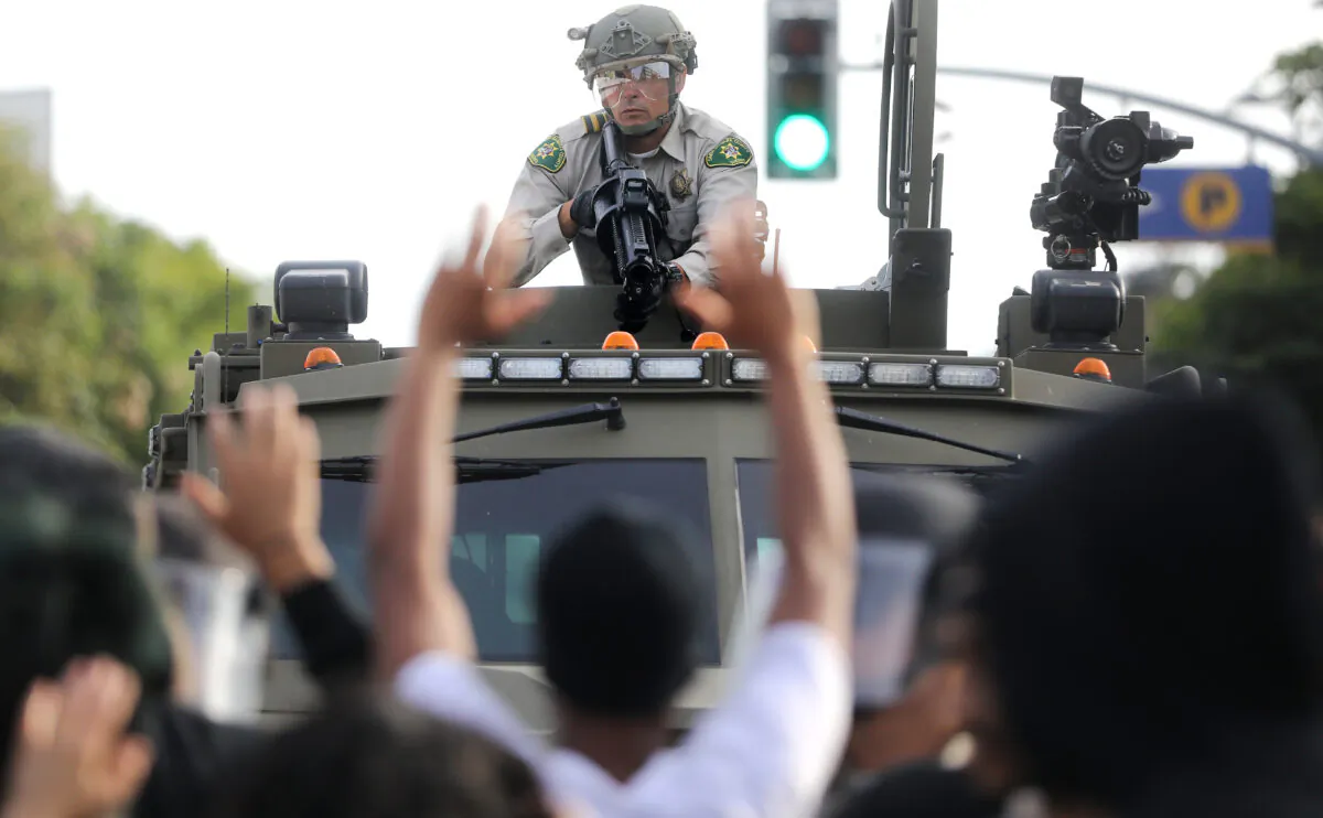 A police officer aims a nonlethal weapon as protesters raise their hands during demonstrations in the aftermath of George Floyd’s death  in Santa Monica, Calif., on May 31, 2020. (Mario Tama/Getty Images)