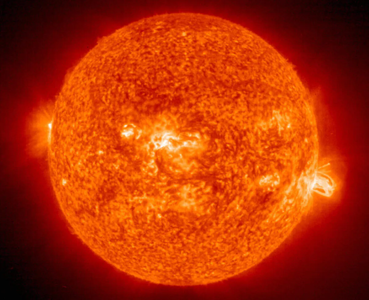A solar flare (R) erupting from giant sunspot 649. The powerful explosion hurled a coronal mass ejection(CME) into space, but it was directed toward Earth on Aug. 19, 2004. (HO/AFP via Getty Images)