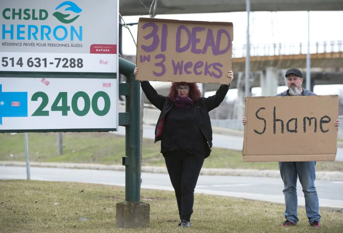 Two people hold protest signs outside Maison Herron, a long-term care home in the Montreal suburb of Dorval, Que., on April 11, 2020. (The Canadian Press/Graham Hughes)