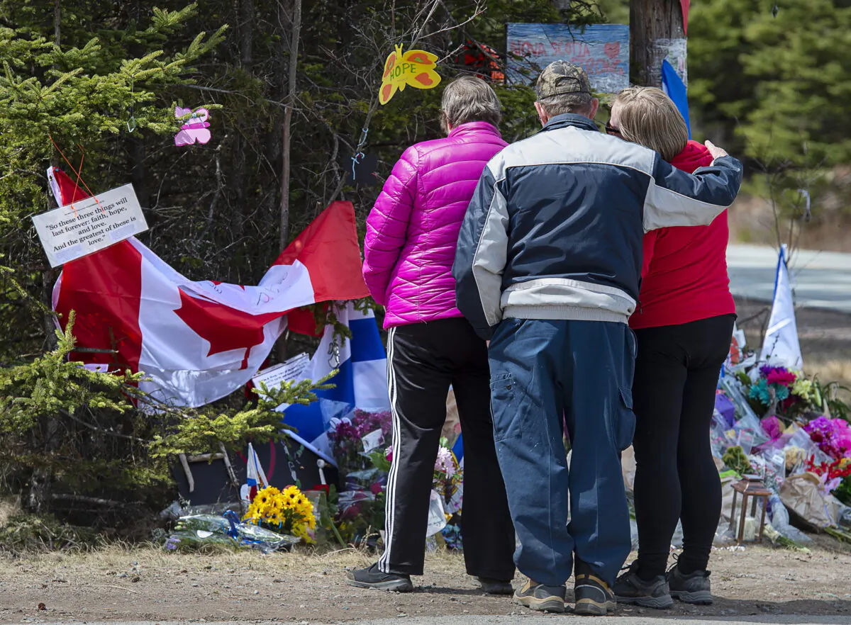 A family pays their respects to victims of the mass killings at a checkpoint on Portapique Road in Portapique, N.S. on April 24, 2020. (The Canadian Press/Andrew Vaughan)