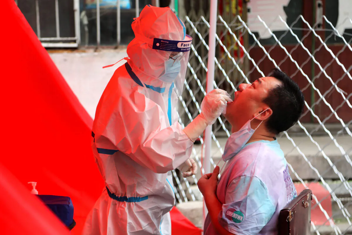 A medical worker takes a swab sample from a resident to be tested for the CCP virus on a street in Mudanjiang, China, on June 3, 2020. (STR/AFP via Getty Images)