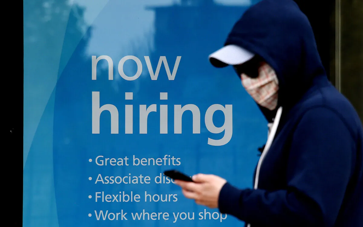 A man wearing a face mask walks past a sign "Now Hiring" in front of a store amid the COVID-19 pandemic, in Arlington, Va., on May 14, 2020. (Olivier Douliery/AFP/Getty Images)