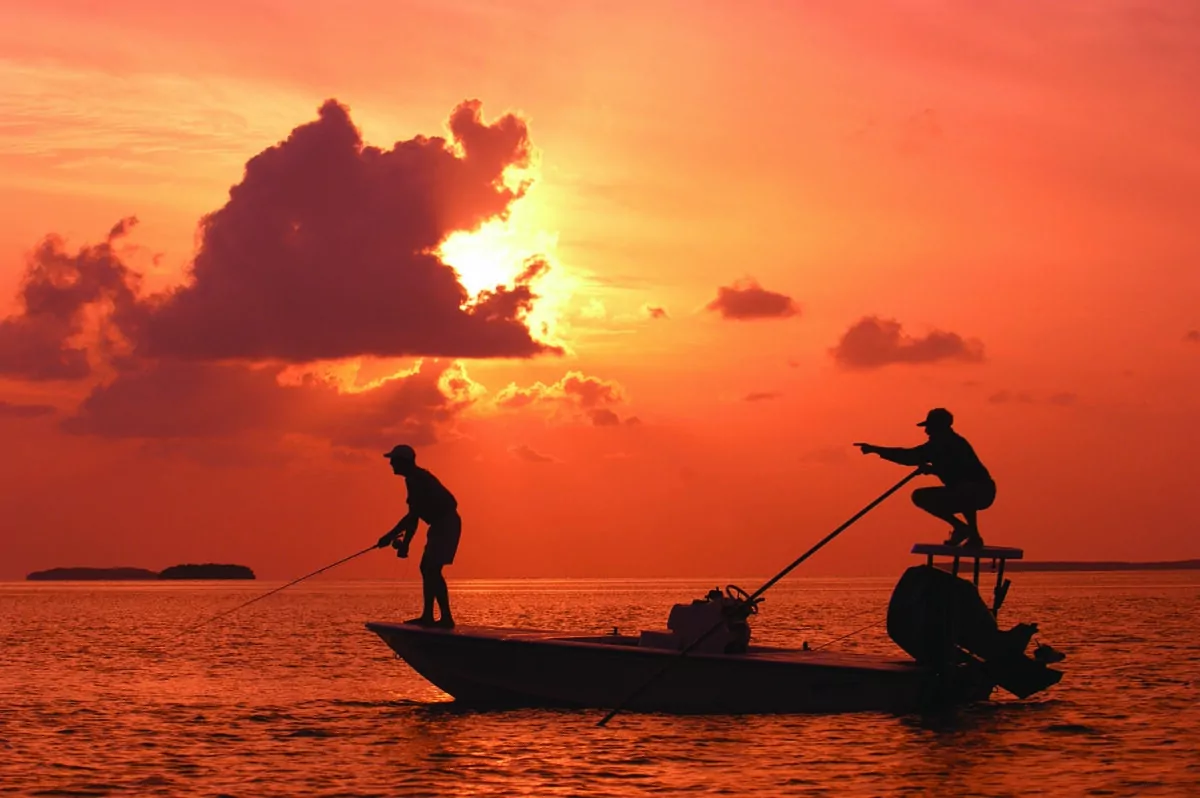 As the sun sets, a guide (R) points his angler to a bonefish off Islamorada. More than 200 International Game Fish Association saltwater world records have been set in the Florida Keys. (Bob Krist/Florida Keys News Bureau)