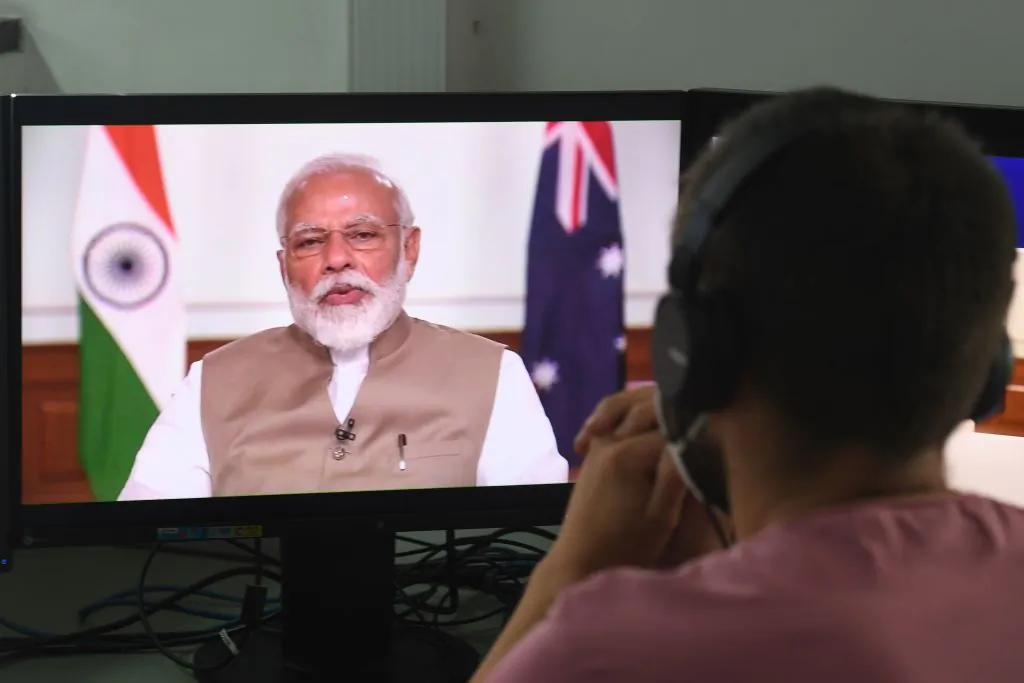 A man wearing a face-mask watches on a monitor Indian Prime Minister Narendra Modi speak during a bilateral virtual summit with Australian Prime Minister Scott Morrison, at an office in New Delhi on June 4, 2020. (Prakash Singh/AFP via Getty Images)