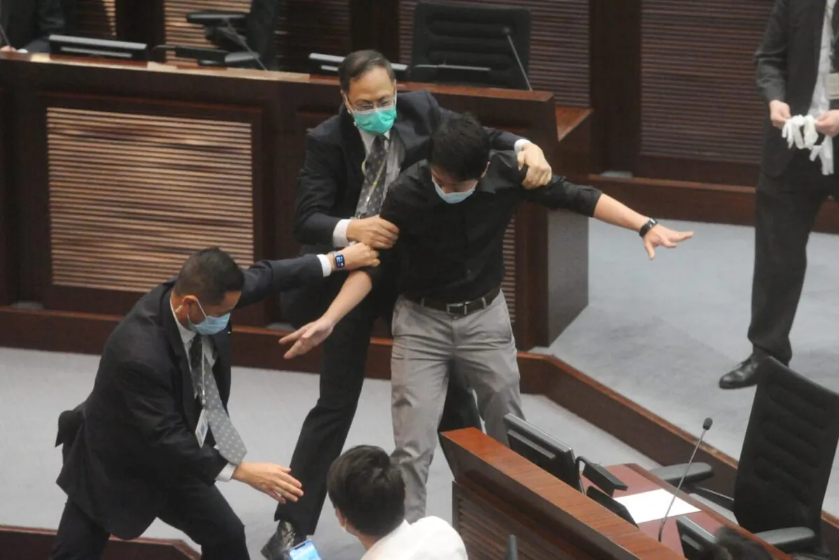Hui Chi-fung, a lawmaker from the local Democratic Party, is restrained by security guards at Hong Kong’s Legislative Council (LegCo) just before a vote on the controversial national anthem bill on June 4, 2020. (Song Bilung/The Epoch Times)