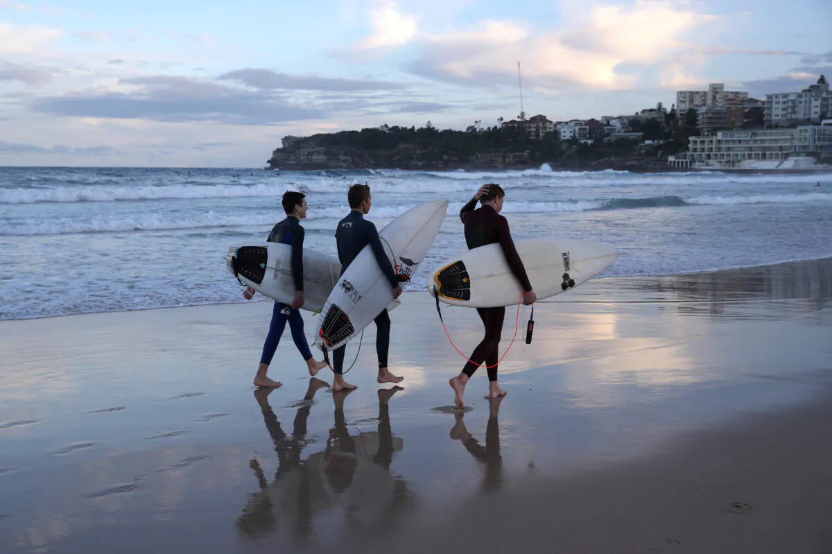 Surfers walk along the water's edge amidst easing restrictions at Bondi Beach in Sydney, Australia, May 27, 2020. (REUTERS/Loren Elliott)