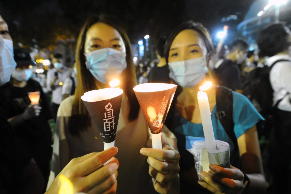 Two people hold up candles during a vigil at Victoria Park, Hong Kong, on June 4, 2020. (Song Bilung/The Epoch Times) 