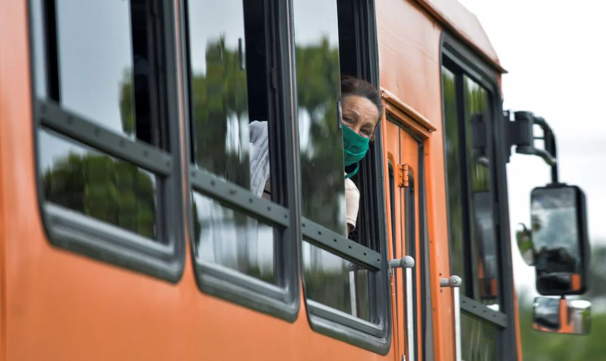 A woman wearing a face mask amid concern over the spread of the COVID-19 coronavirus, peers out the window of a bus in Havana on June 2, 2020. (Yamil Lage/AFP via Getty Images)