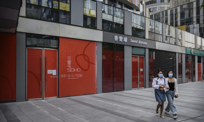 Chinese women wear   protective masks as they walk by shops that have gone out of business, in a shopping district in Beijing on April 28, 2020. (Kevin Frayer/Getty Images)