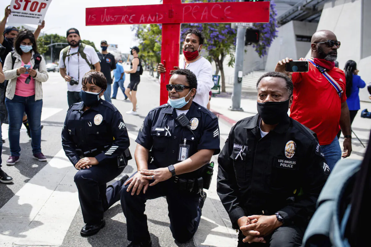 Los Angeles police officers take a knee with clergy and marchers at LAPD Headquarters during a demonstration demanding justice for George Floyd in Los Angeles on June 2, 2020. (Sarah Reingewirtz/The Orange County Register via AP, File)